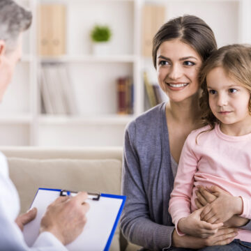 Pediatrician doctor examining child. Mother holding baby in her hands.