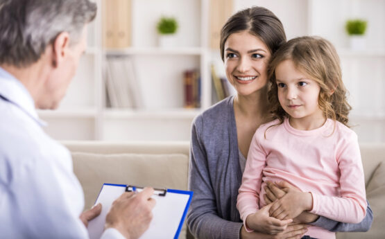 Pediatrician doctor examining child. Mother holding baby in her hands.